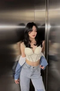 Young woman wearing a light green corset top and light blue jeans.