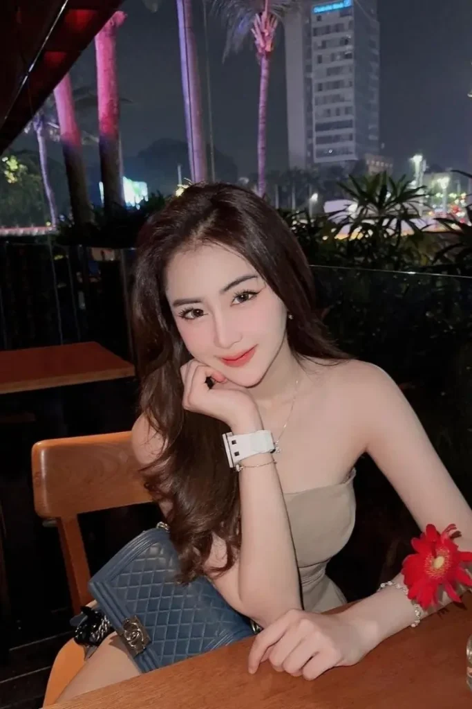 Attractive young woman in a beige dress sits at a restaurant table.