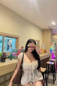 Woman in white top and polka dot shorts standing indoors with stools and decor.