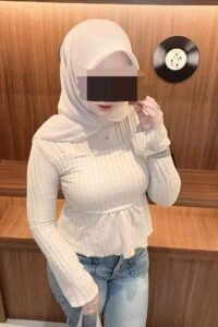 Woman in hijab and cream top, Yati style, with jeans and a vinyl record in the background.