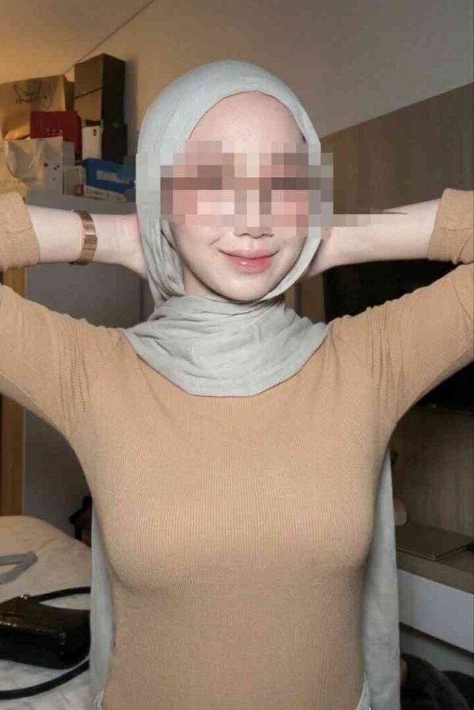 Young Malay woman in hijab, smiling, wearing a beige top